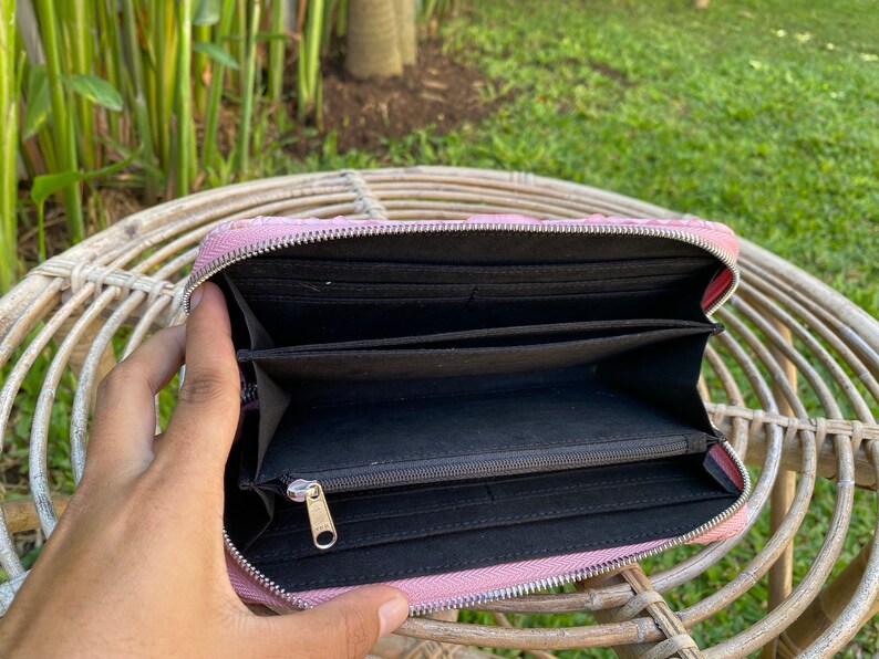 Peut inclure: Un portefeuille zipp&eacute; rose avec un int&eacute;rieur noir et plusieurs compartiments. Le portefeuille est ouvert et l'int&eacute;rieur est visible.