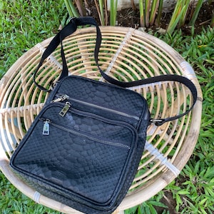 May include: Black leather crossbody bag with a snakeskin pattern and multiple zipped compartments.