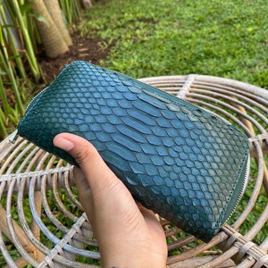 Peut inclure: Un portefeuille en cuir de serpent vert fonc&eacute; avec une fermeture &agrave; glissi&egrave;re.