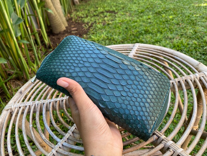 Peut inclure: Un portefeuille en cuir de serpent vert fonc&eacute; avec une fermeture &agrave; glissi&egrave;re.