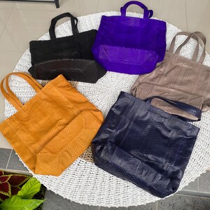 Puede incluir: Cinco bolsos de mano diferentes hechos de piel de serpiente. Los bolsos son de varios colores, incluyendo negro, morado, marr&oacute;n, naranja y azul.