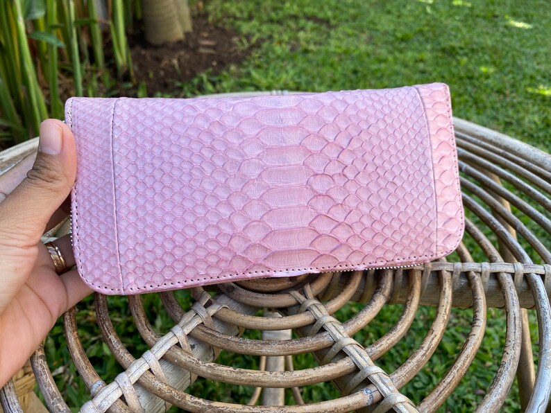 Peut inclure: Un portefeuille en cuir de serpent rose avec une fermeture &eacute;clair.