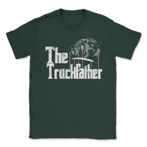 Op de afbeelding: Donkergroen t-shirt met een witte afbeelding van een monstertruck en de tekst "The Truckfather". Het ontwerp heeft een verweerde lettertype en een gedetailleerde illustratie van de truck.