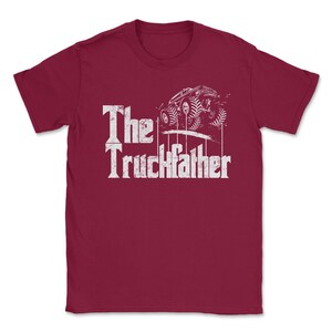 Op de afbeelding: Bordeauxrood T-shirt met de tekst "The Truckfather" in een verweerde witte letter. Een witte afbeelding van een monstertruck staat boven de tekst. Het shirt heeft een ronde hals.