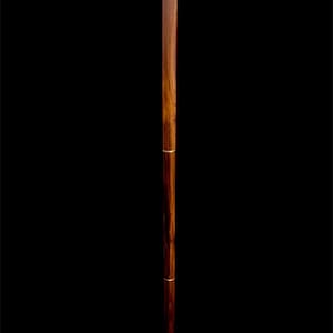 May include: A wooden walking stick with a decorative brass handle. The handle is shaped like a curved horn and has a floral design.