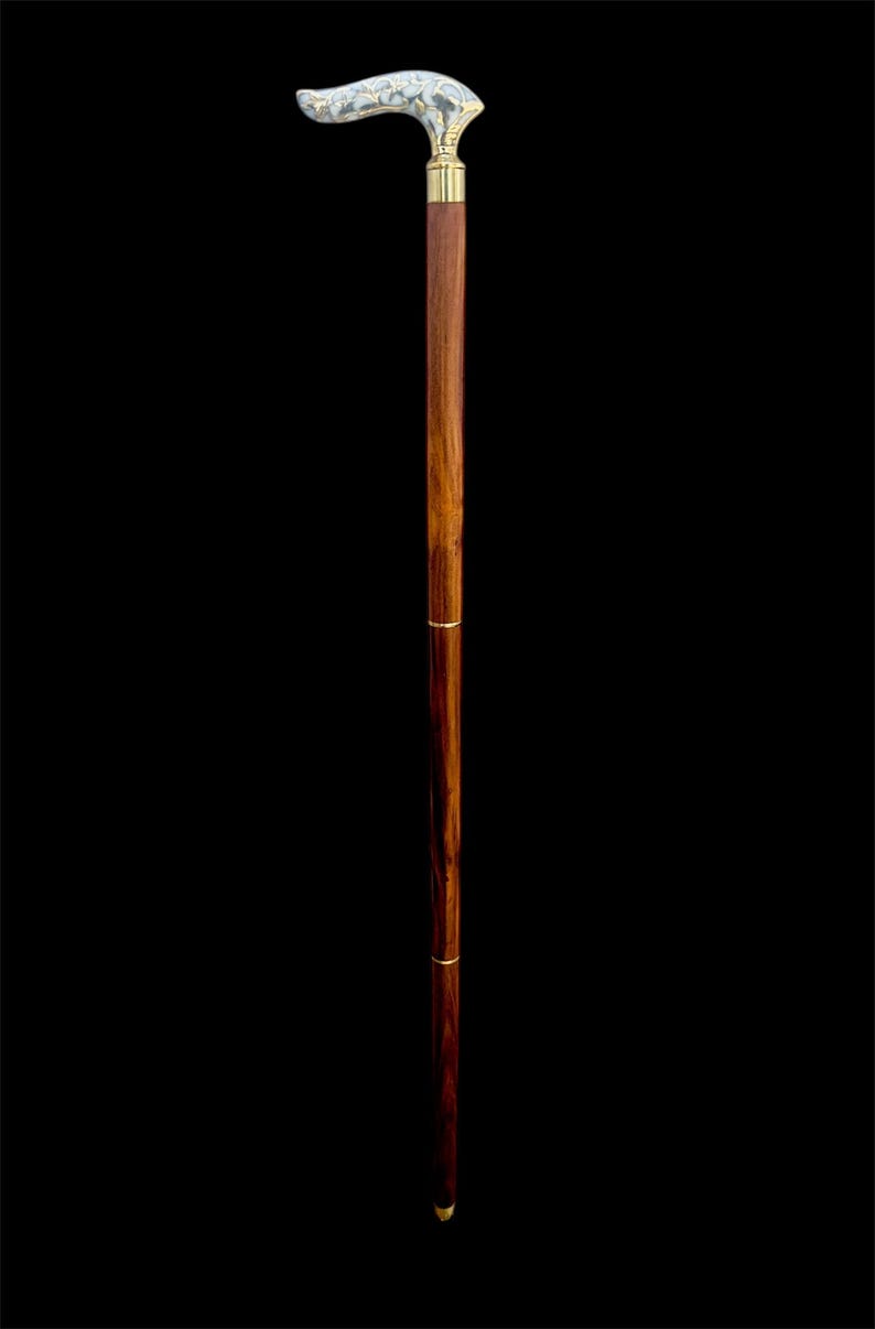 May include: A wooden walking stick with a decorative brass handle. The handle is shaped like a curved horn and has a floral design.