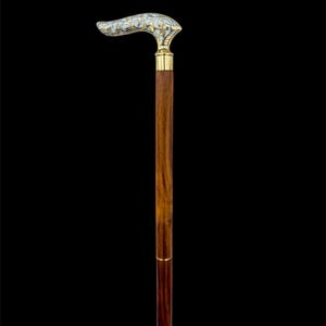 May include: A wooden walking stick with a decorative, white and gold handle. The handle has a floral design.