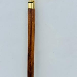 May include: A wooden walking stick with a brass handle featuring a white and gold floral design.