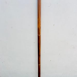 May include: A wooden walking stick with a decorative brass handle. The handle is shaped like a curved horn and has a silver finish.