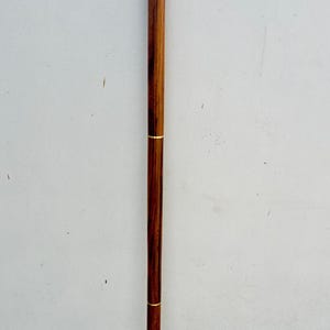 May include: A wooden walking stick with a brass handle featuring an ornate design. The handle is curved and has a gold finish.