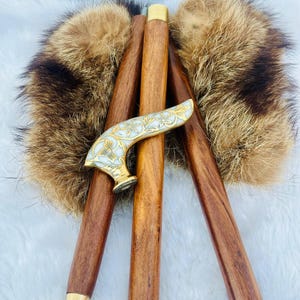 May include: Three wooden walking sticks with a decorative brass handle. The handle is inlaid with white mother of pearl and has a floral design. The sticks are resting on a brown fur surface.