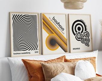 May include: Three framed prints with geometric designs in black and white. The centre print features the text "bauhaus im gewerbemuseum basel!" The right print features the text "weimar juli - sept 1923 bauhaus". The left print features the text "bauhaus ausstellung 1919".