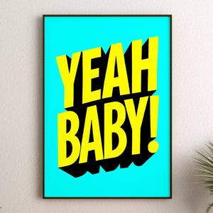 May include: A framed art print with the words "YEAH BABY!" in bold yellow letters with black shadow on a bright turquoise background. The print is in a black frame and is hanging on a white wall.