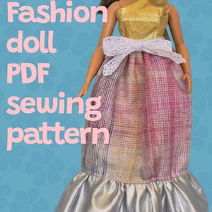Könnte beinhalten: Ein PDF-Schnittmuster für ein Modepuppenkleid. Das Kleid ist in Gold- und Rosatönen mit einem weißen Spitzenband und einem silbernen Rüschen am Saum.