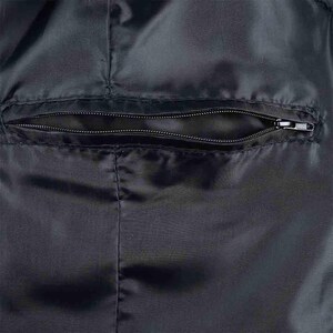 May include: Close-up of a black fabric with a zippered pocket. The pocket is horizontally oriented and sewn into the fabric. The zipper is closed, and the fabric has a slight sheen.