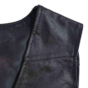 May include: Close-up of a black leather vest. The vest has a textured surface and a V-neck design. The stitching is visible along the seams. The vest appears to be new.