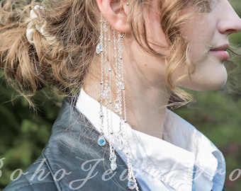 May include: Silver ear cuff with multiple delicate chains and dangling crystals. The ear cuff is worn on the left ear and cascades down. The image also shows a black leather jacket and a white shirt. The text "Boho Jewel Love" is visible.