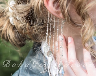 May include: Silver dangle earrings with multiple chains, beads, and charms, including a crescent moon and a faceted crystal. The earrings are worn by a person with blonde hair and a black leather jacket. The text "Boho Jewels Trove" is visible.