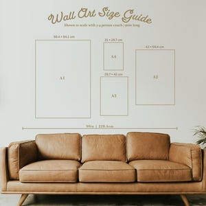 May include: A wall art size guide with dimensions in centimetres and inches, shown to scale with a couch. The guide includes sizes A1, A2, A3, and A4, with a 90-inch (228.6 cm) reference. A brown leather couch is in the foreground.
