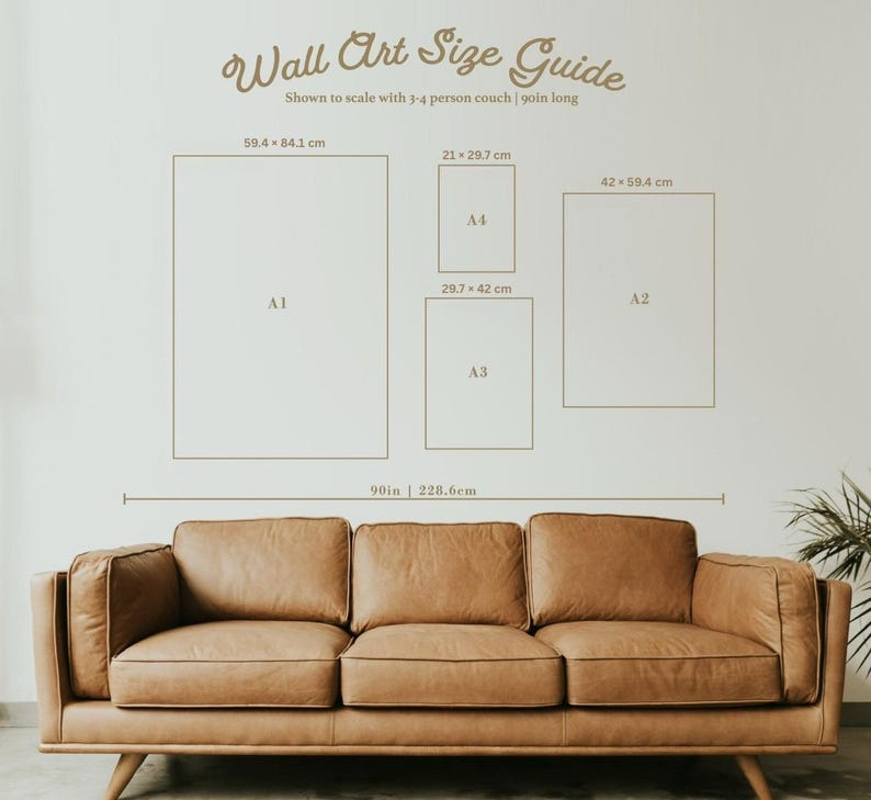 May include: A wall art size guide with dimensions in centimetres and inches, shown to scale with a couch. The guide includes sizes A1, A2, A3, and A4, with a 90-inch (228.6 cm) reference. A brown leather couch is in the foreground.