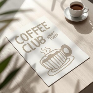 May include: A white rectangular sign with the words "COFFEE CLUB SERVED FRESH" in a light brown color. A light brown illustration of a coffee cup is below the text. A white coffee cup and saucer are on the right.