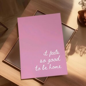 May include: Pink and white gradient background with the text "it feels so good to be home" written in white cursive.