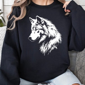 Op de afbeelding: Zwart sweatshirt met een witte wolf grafische print. De wolf kijkt naar links en heeft een gedetailleerde omtrek.