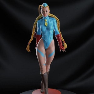 以下が含まれることがあります： ストリートファイターのビデオゲームシリーズの女性キャラクターの精巧なフィギュア。フィギュアはダイナミックなポーズで、水色のボディスーツに赤いアームバンドと茶色のブーツを着用しています。ベースは黒で、赤いアクセントとストリートファイターのロゴが付いています。