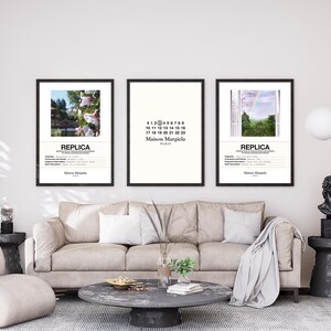 May include: Three framed posters with black frames hanging on a white wall above a beige sofa. The posters feature a floral scene, a white background with black text, and a landscape with a rainbow. The text on the posters reads "REPLICA" and "Maison Margiela Paris".