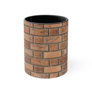 Op de afbeelding: Een cilindrische koffiemok met een bakstenen muurontwerp. De mok heeft een zwart interieur en een rondom bedrukte buitenkant met een verweerd baksteenpatroon in bruin-, beige- en grijstinten. De mok is gemaakt van keramiek.