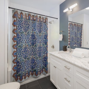 May include: A shower curtain with a blue and white floral pattern. The pattern is reminiscent of traditional Turkish tilework. The curtain is hung in a bathroom with a white tiled wall and a white vanity.