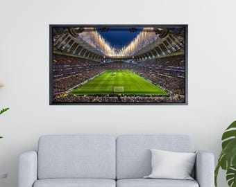 May include: A black and white photograph of a large stadium filled with people watching a football match. The stadium is lit up with lights and there are fireworks in the air.