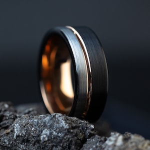May include: A black and rose gold tungsten carbide ring with a brushed finish and a polished silver band.