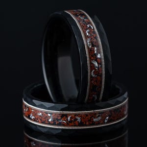 May include: Two black rings with a red and silver inlay. The rings are stacked on top of each other.