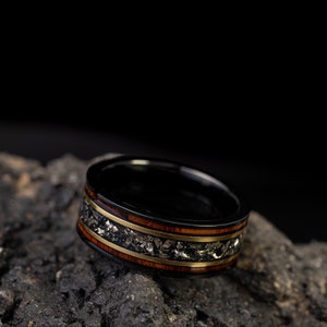 Peut inclure: Une bague noire avec un incrustation dor&eacute;e et brune. La bague est en bois et en m&eacute;tal et a un design unique.
