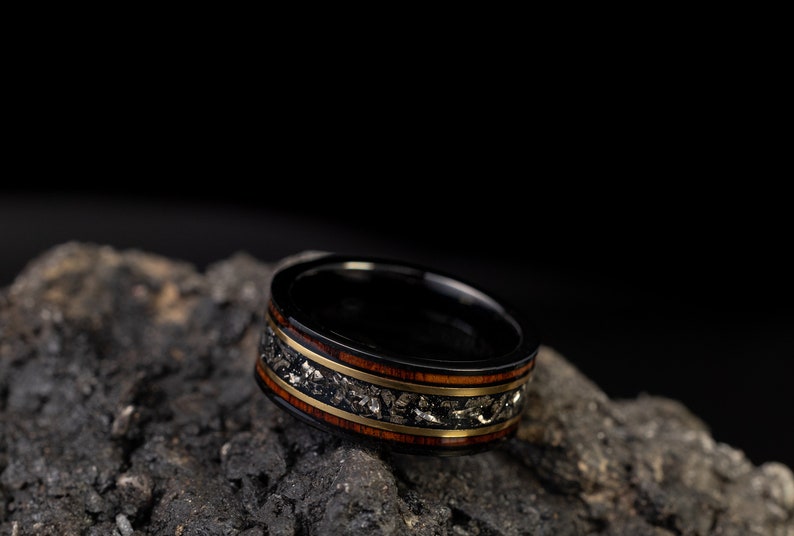 Peut inclure: Une bague noire avec un incrustation dor&eacute;e et brune. La bague est en bois et en m&eacute;tal et a un design unique.
