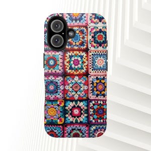Könnte beinhalten: Eine rechteckige Smartphone-Hülle mit einem lebendigen, mehrfarbigen Granny-Square-Häkelmuster. Das Design besteht aus sich wiederholenden quadratischen Motiven in Rot-, Blau-, Gelb-, Rosa- und Weißtönen mit einem schwarzen Kameraausschnitt oben links.