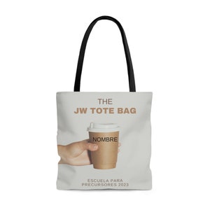 May include: A gray tote bag with black handles. The bag has the text "THE JW TOTE BAG" printed on it. There is a brown paper cup with a white lid and the word "NOMBRE" printed on it. The cup is being held by a hand. The text "ESCUELA PARA PRECURSORES 2023" is printed at the bottom of the bag.