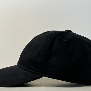 May include: A black baseball cap with a curved brim. The cap is made of a soft, cotton fabric.