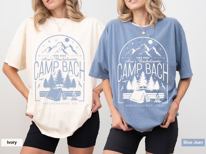May include: Two women wearing oversized t-shirts with a camping theme graphic. The text on the shirts reads "JUNE 2024 Ava's Bachelorette CAMP BACH BRECKENRIDGE, CO". The shirts are in ivory and blue jean colors.
