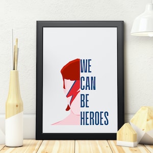 May include: A black framed print with a white background and a red and blue illustration of David Bowie's face. The text "WE CAN BE HEROES" is printed in blue letters.