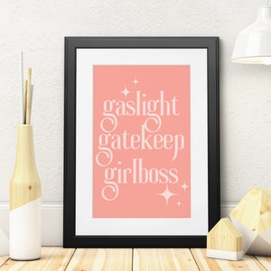 Peut inclure: Une impression encadrée avec un fond rose et du texte blanc qui dit "gaslight gatekeep girlboss" avec des étoiles de chaque côté du texte.