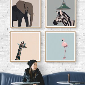 May include: Four framed illustrations of animals: an elephant, a zebra, a giraffe, and a flamingo. The illustrations are in a minimalist style with a light background. The frames are light wood and are hanging on a white brick wall.