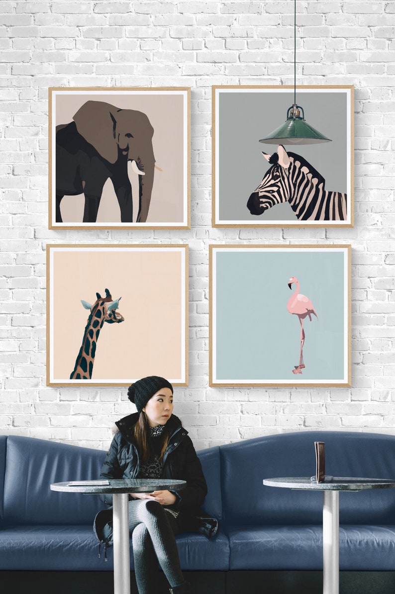 May include: Four framed illustrations of animals: an elephant, a zebra, a giraffe, and a flamingo. The illustrations are in a minimalist style with a light background. The frames are light wood and are hanging on a white brick wall.