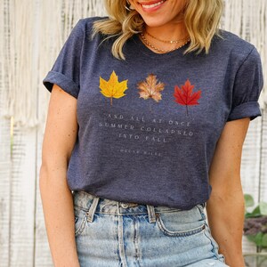 Puede incluir: Una camiseta azul marino con un gr&aacute;fico de tres hojas de oto&ntilde;o y la cita "Y de repente el verano se derrumb&oacute; en oto&ntilde;o." de Oscar Wilde.