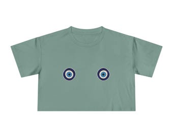 May include: A sage green cropped t-shirt with two blue evil eye charms on the front.