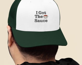 May include: A white and green trucker hat with the text "I Got The Sauce" and a small image of a pot of sauce.