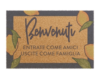 May include: A brown coir doormat with a grey border and a welcome message in Italian that reads "Benvenuti" and "Entrate come amici uscite come famiglia". The doormat is decorated with yellow lemons and green leaves.