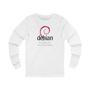 May include: White long-sleeved top featuring the word "debian" in black font and a red swirl logo. The text "So stable it's not even funny" is printed below the word "debian".