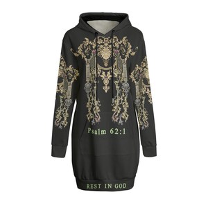 May include: Black hooded sweatshirt dress with an ornate gold and cream design. The text "Psalm 62:1" and "REST IN GOD" are printed on the front. The dress has a front pocket and a drawstring hood.